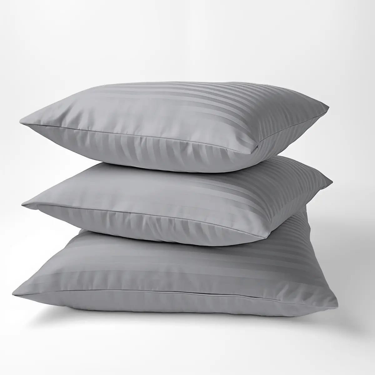 Három párna egymáson, szürke luxus ágyneműhuzat párnahuzatával