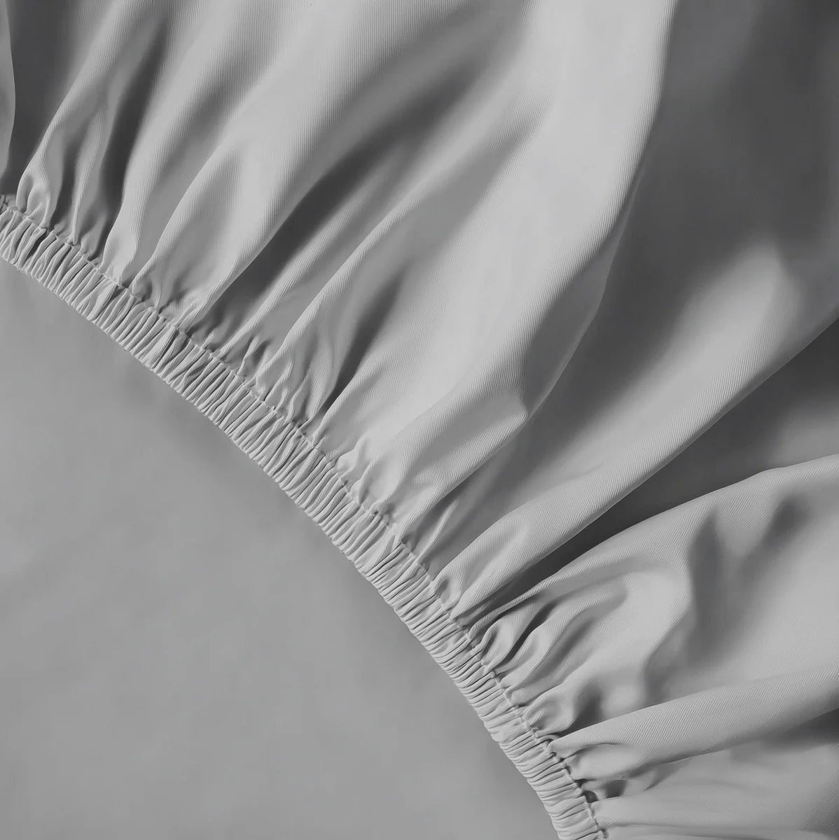 Szürke lepedő rugalmas gumis része közelről