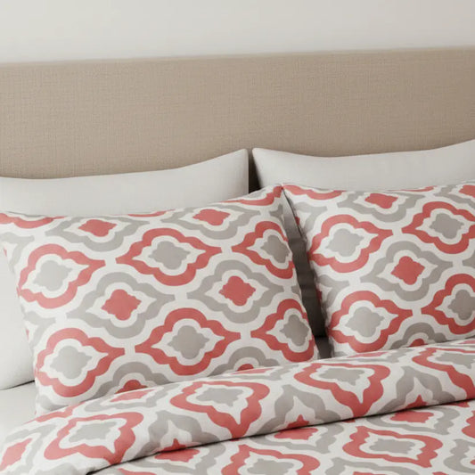 Rózsaszín és szürke geometriai mintás ágyneműhuzat franciaágyon, közelről